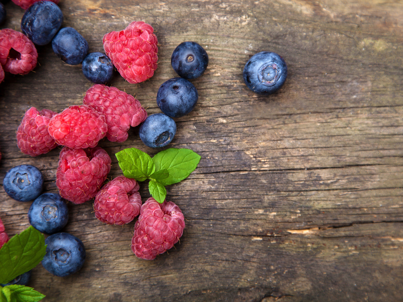 Голубые ягоды черники и красные ягоды малины на деревянном столе