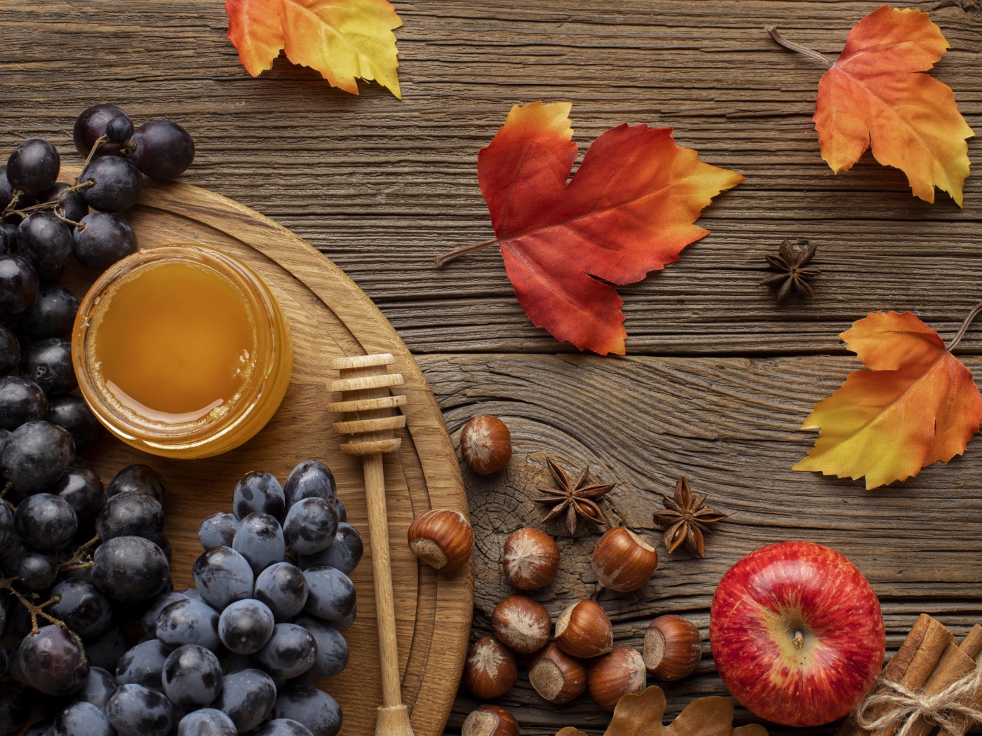 Мед на столе с виноградом, орехами и яблоками