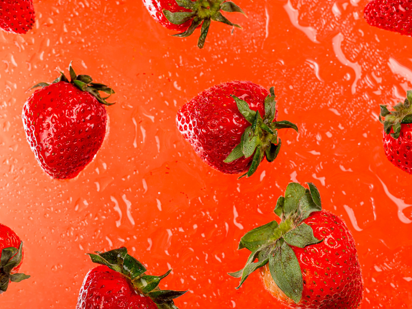 Красная клубника в воде на оранжевом фоне 