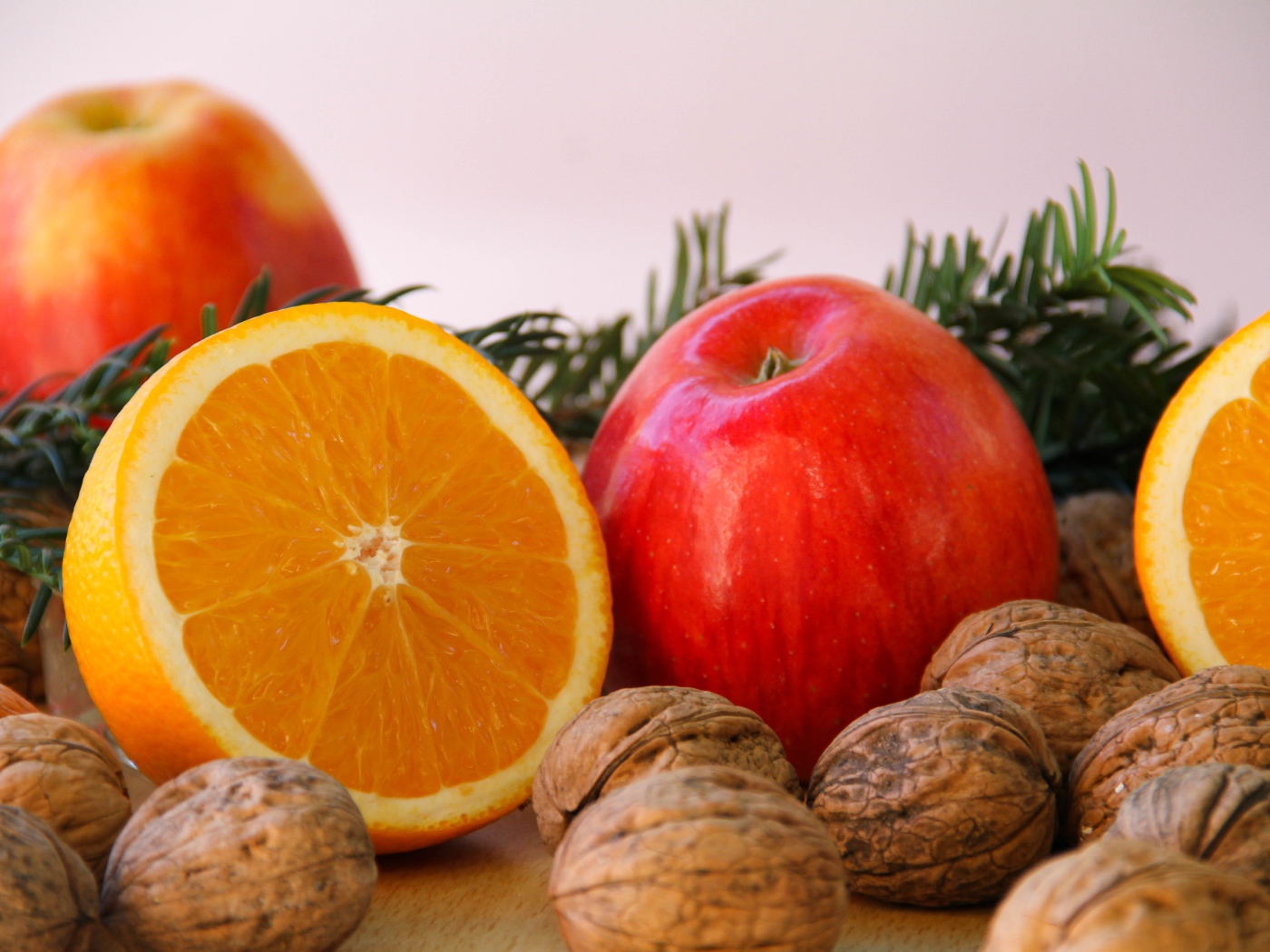 Грецкие орехи с апельсинами и яблоками на сером фоне 