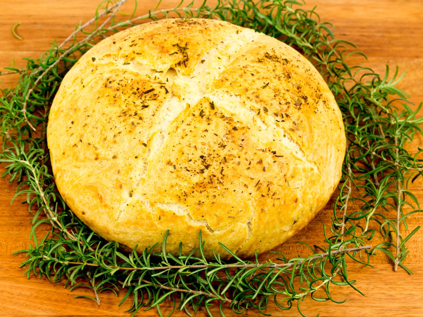 Буханка свежего ароматного хлеба с розмарином на столе