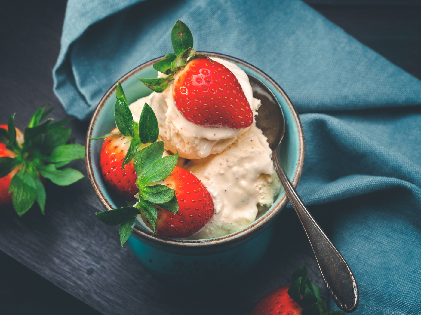 Сливочное мороженое с ягодами клубники в чашке с ложкой