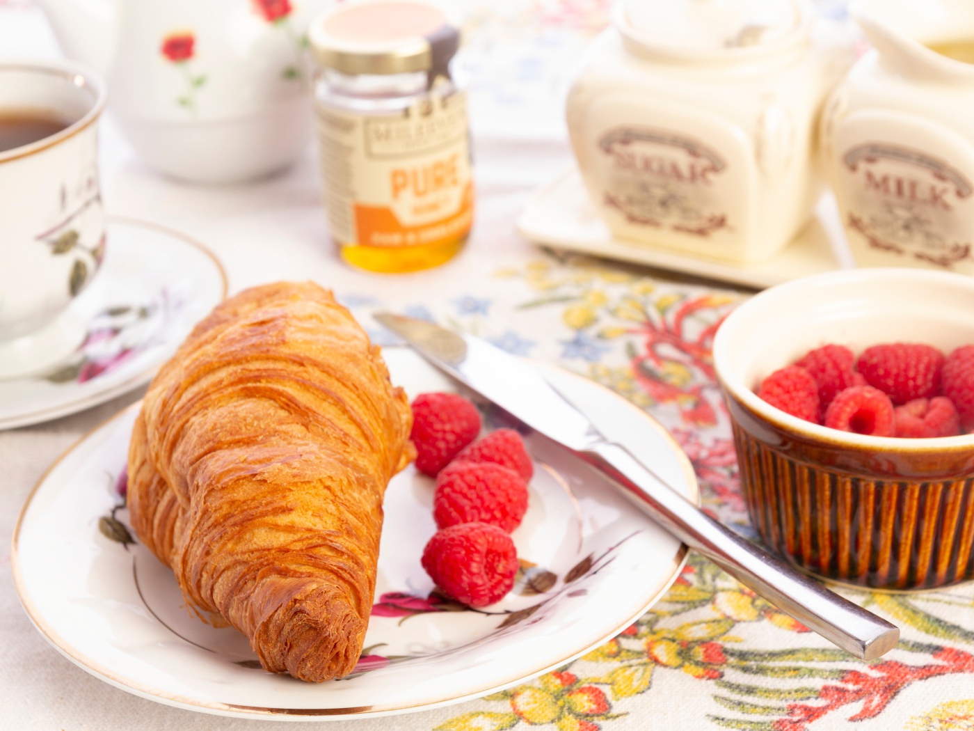 Круассан на тарелке со свежей малиной