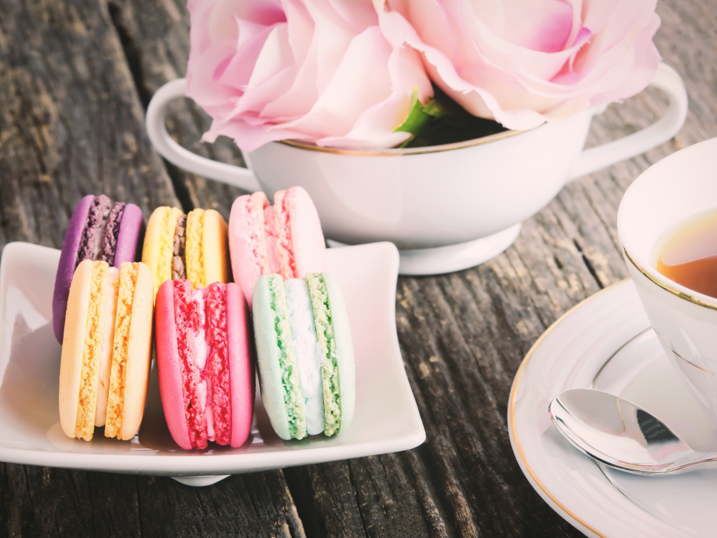 Десерт макарон на столе с чаем и цветами розы