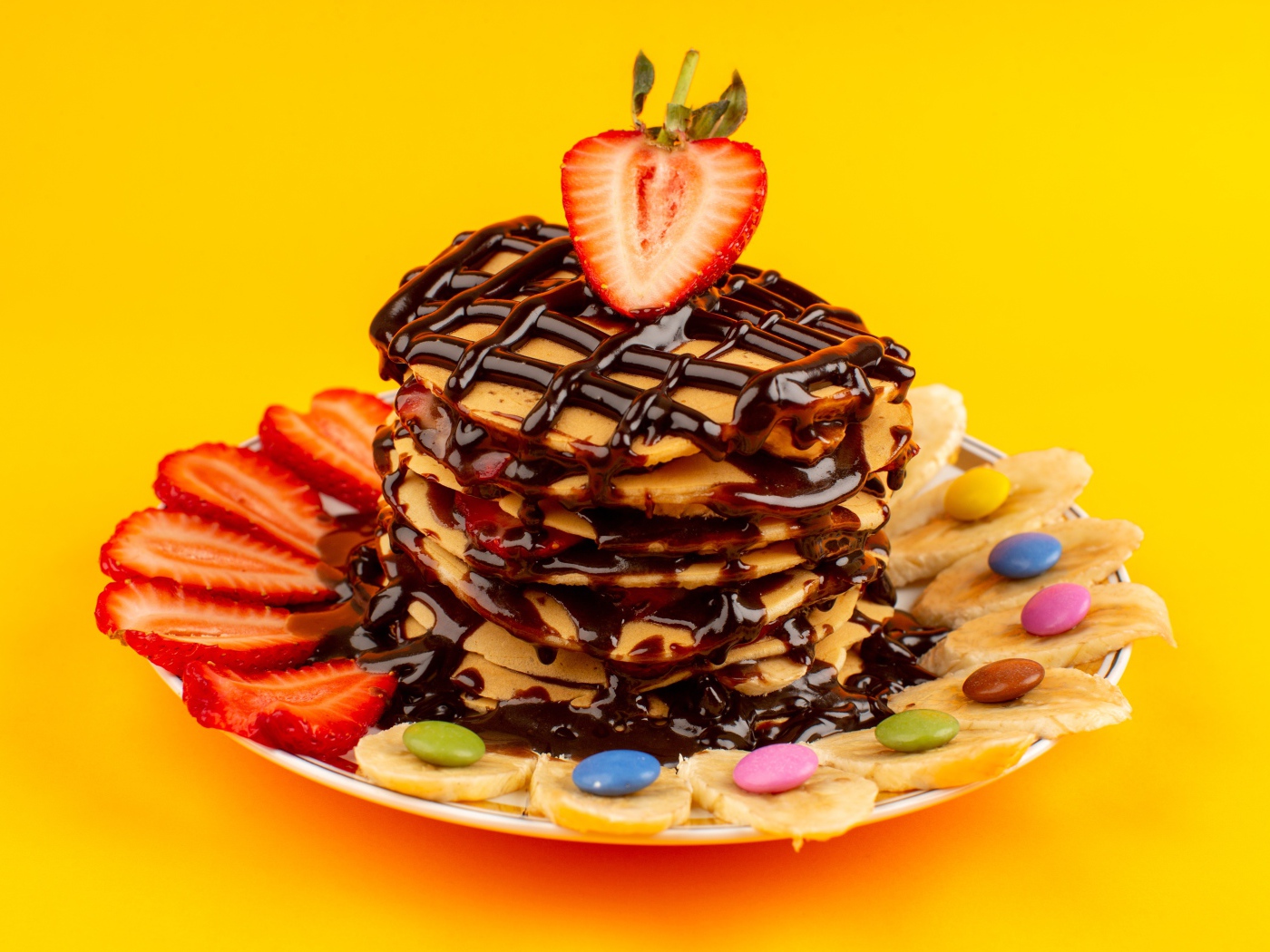 Оладьи с шоколадом, клубникой и бананом на желтом фоне 
