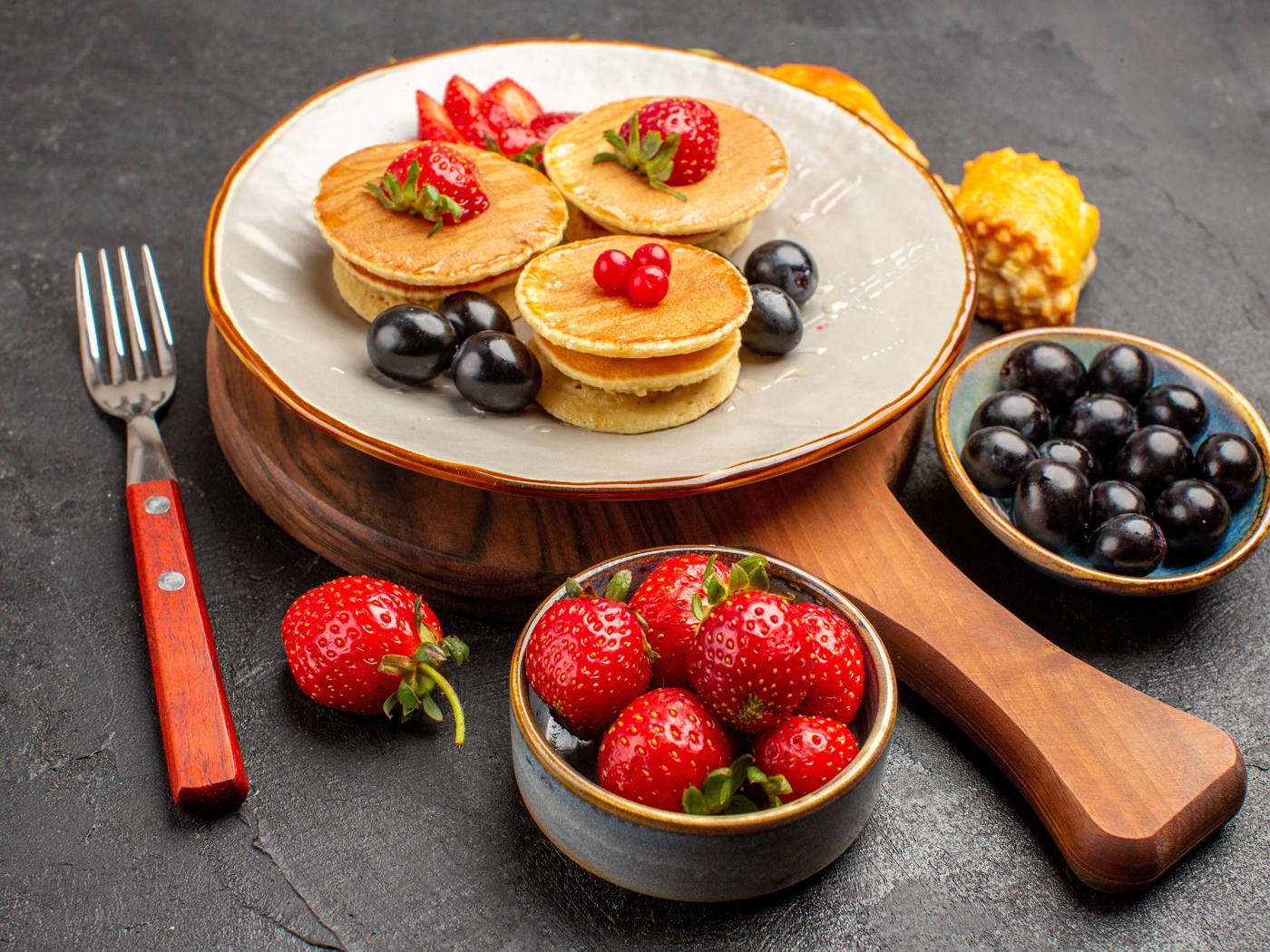 Оладьи с виноградом и клубникой на тарелке 