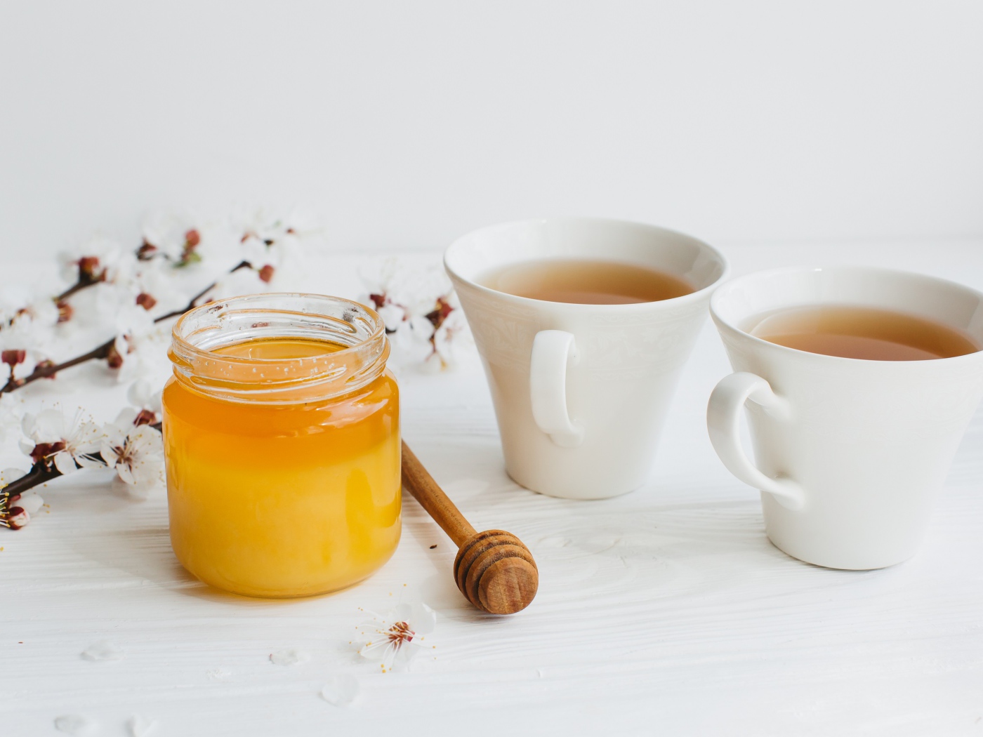 Мед на столе с чаем и цветами абрикоса