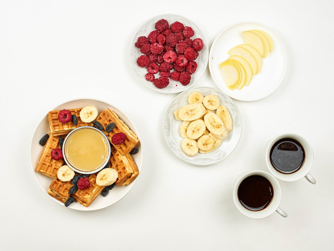 Сладкие вафли с малиной и бананами на столе  с кофе