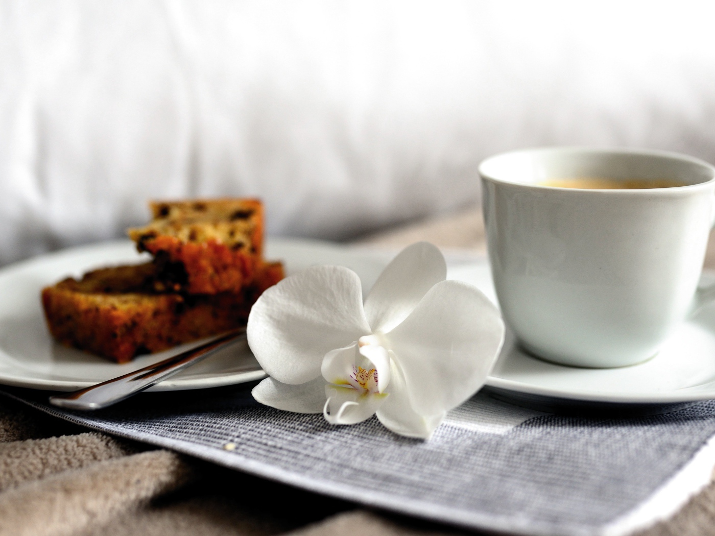 Чашка кофе на столе с цветком орхидеи и кусочками кекса 