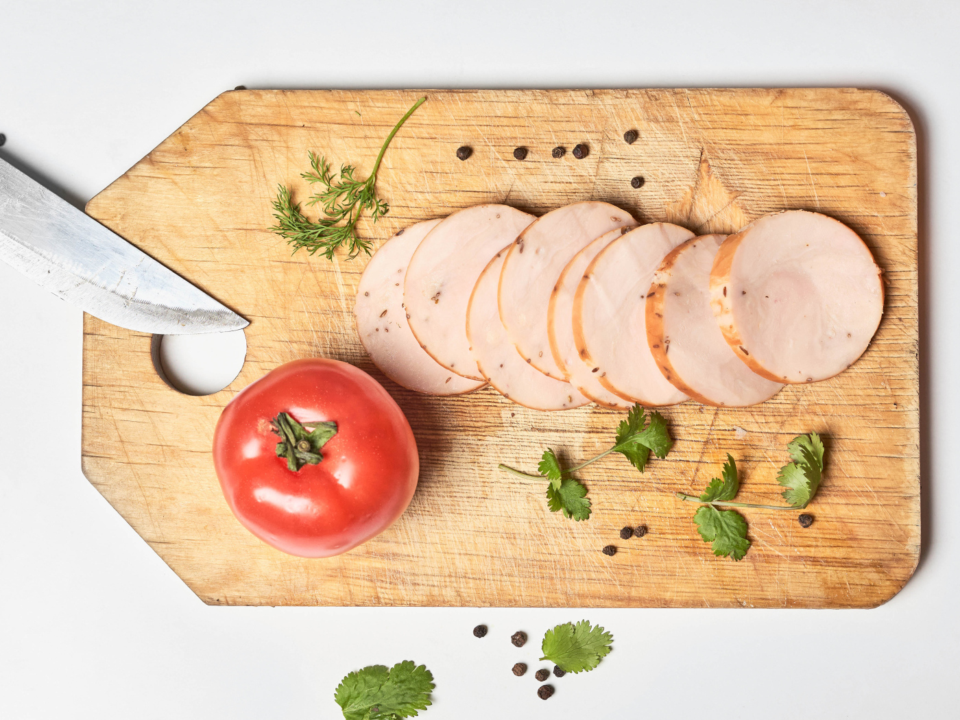 Ветчина на разделочной доске с помидором