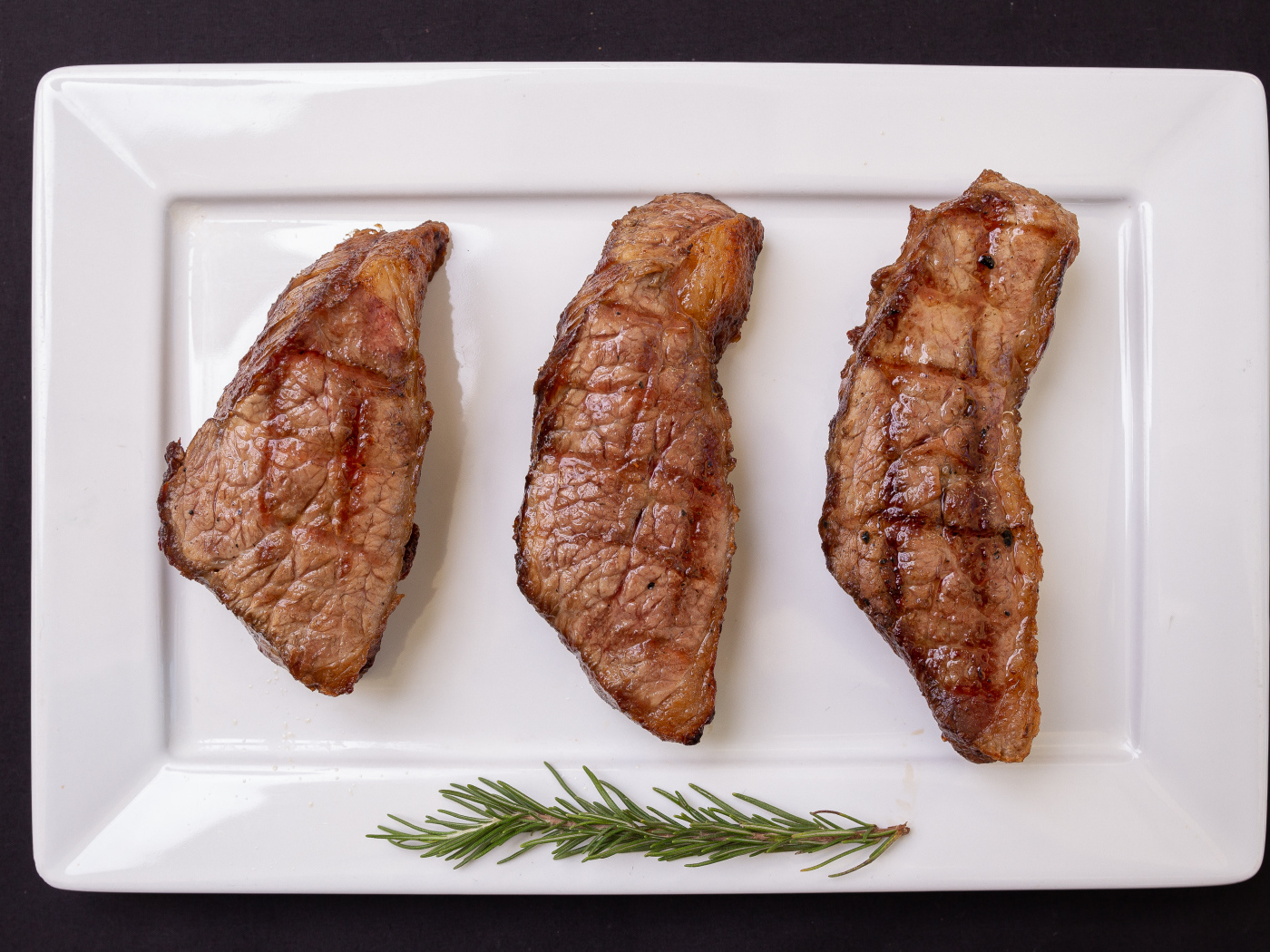 Три куска жареного мяса на большой белой тарелке