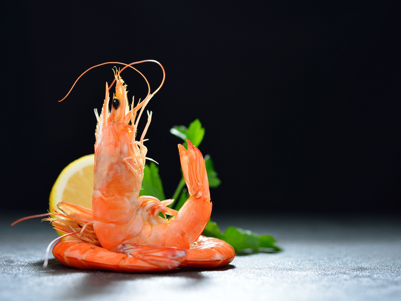 Boiled shrimp with lemon on a black background