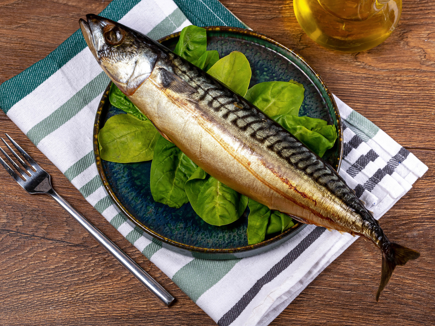 Большая жирная скумбрия на тарелке с базиликом