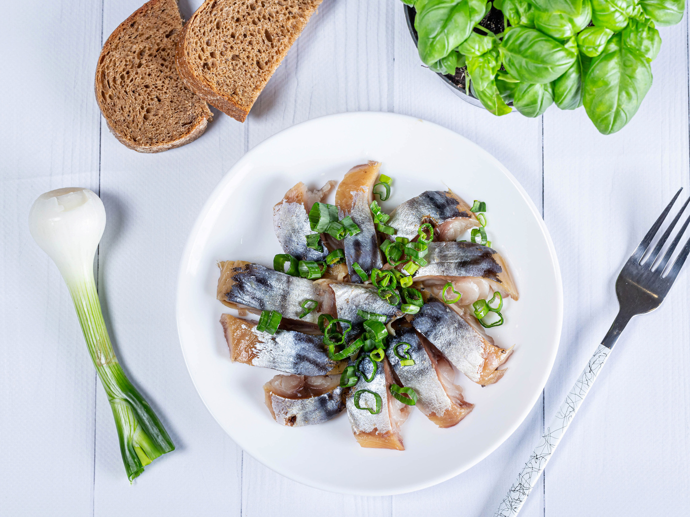 Куски скумбрии на столе с луком, хлебом и базиликом
