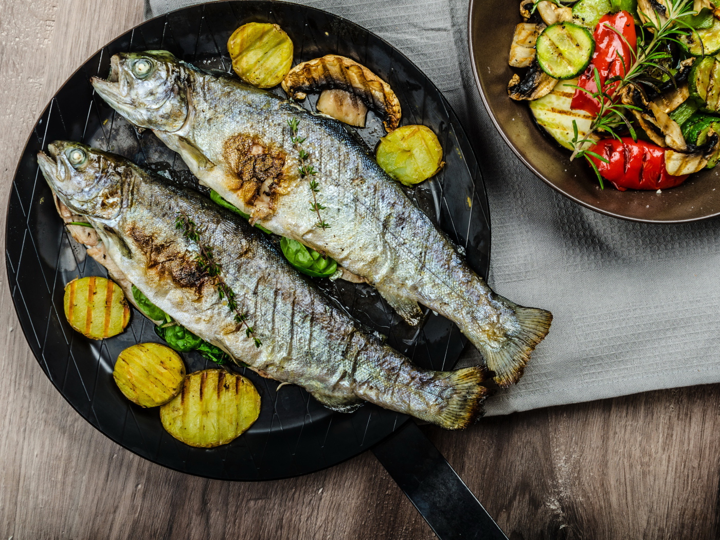 Две рыбины на сковороде с овощами