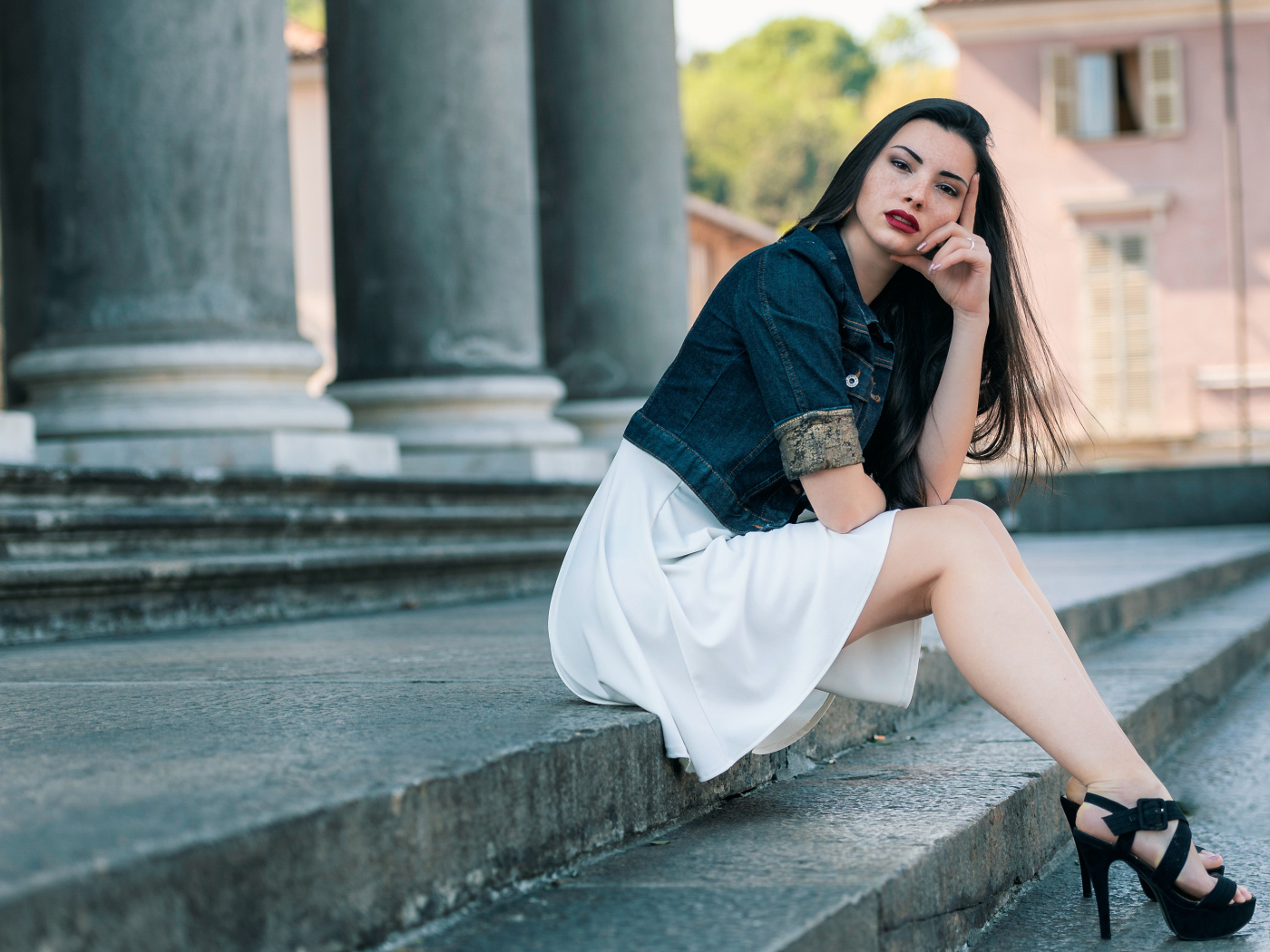 Девушка в белом платье сидит на ступеньках