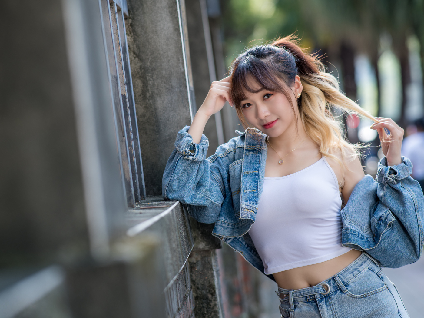 Девушка азиатка в джинсовой куртке у забора 
