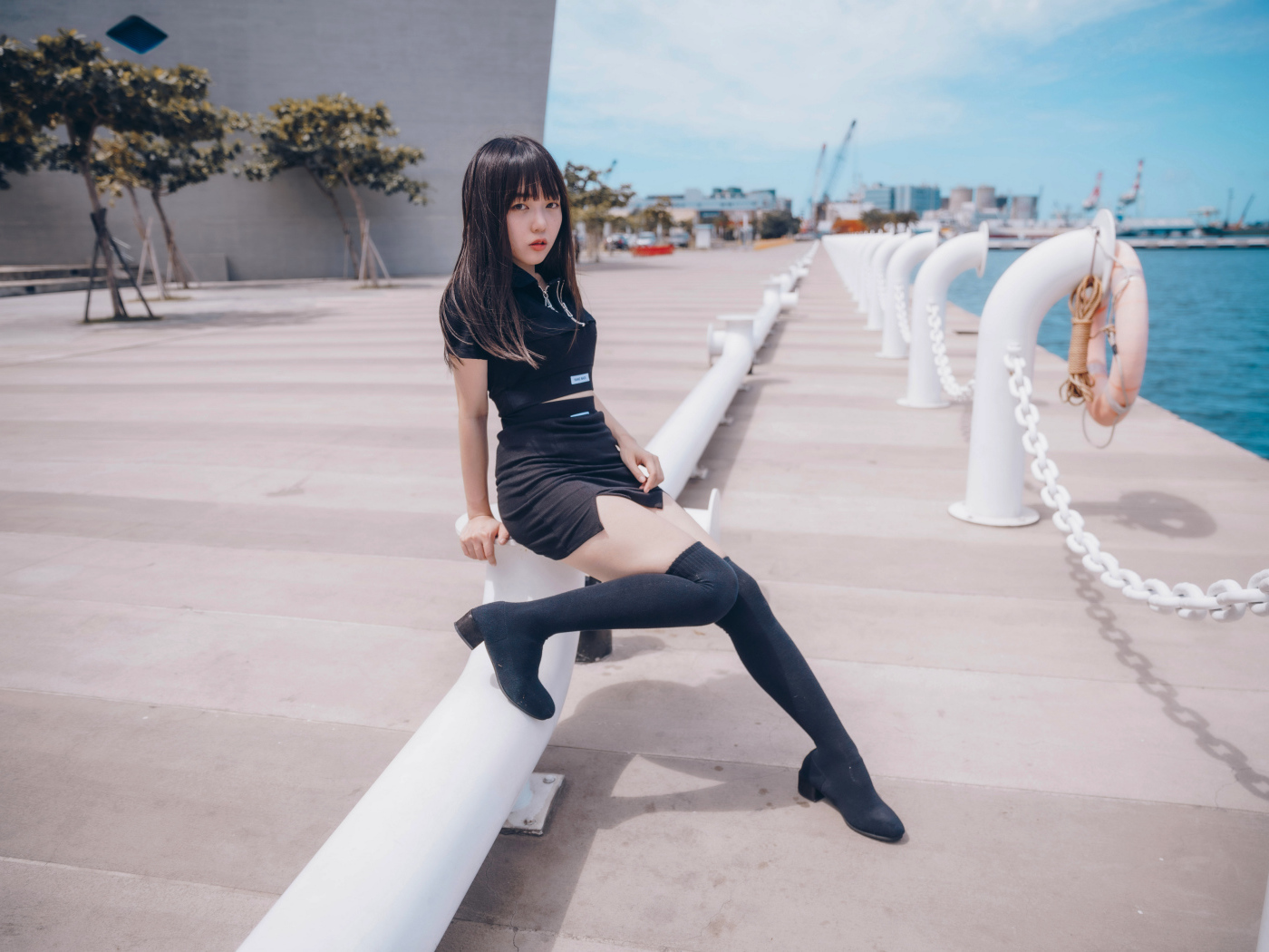 Девушка азиатка в черном костюме на пристани 
