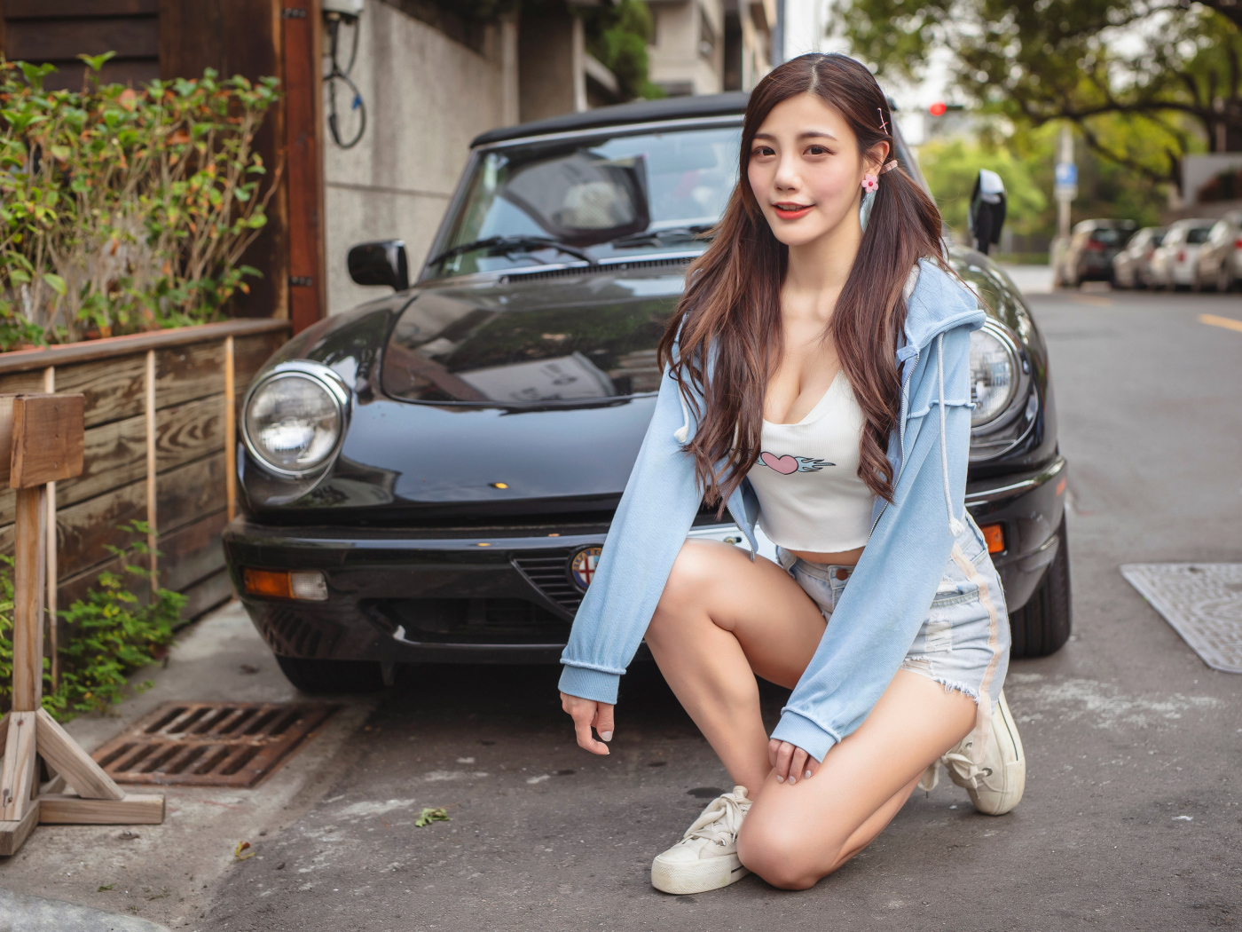 Девушка азиатка сидит возле машины 