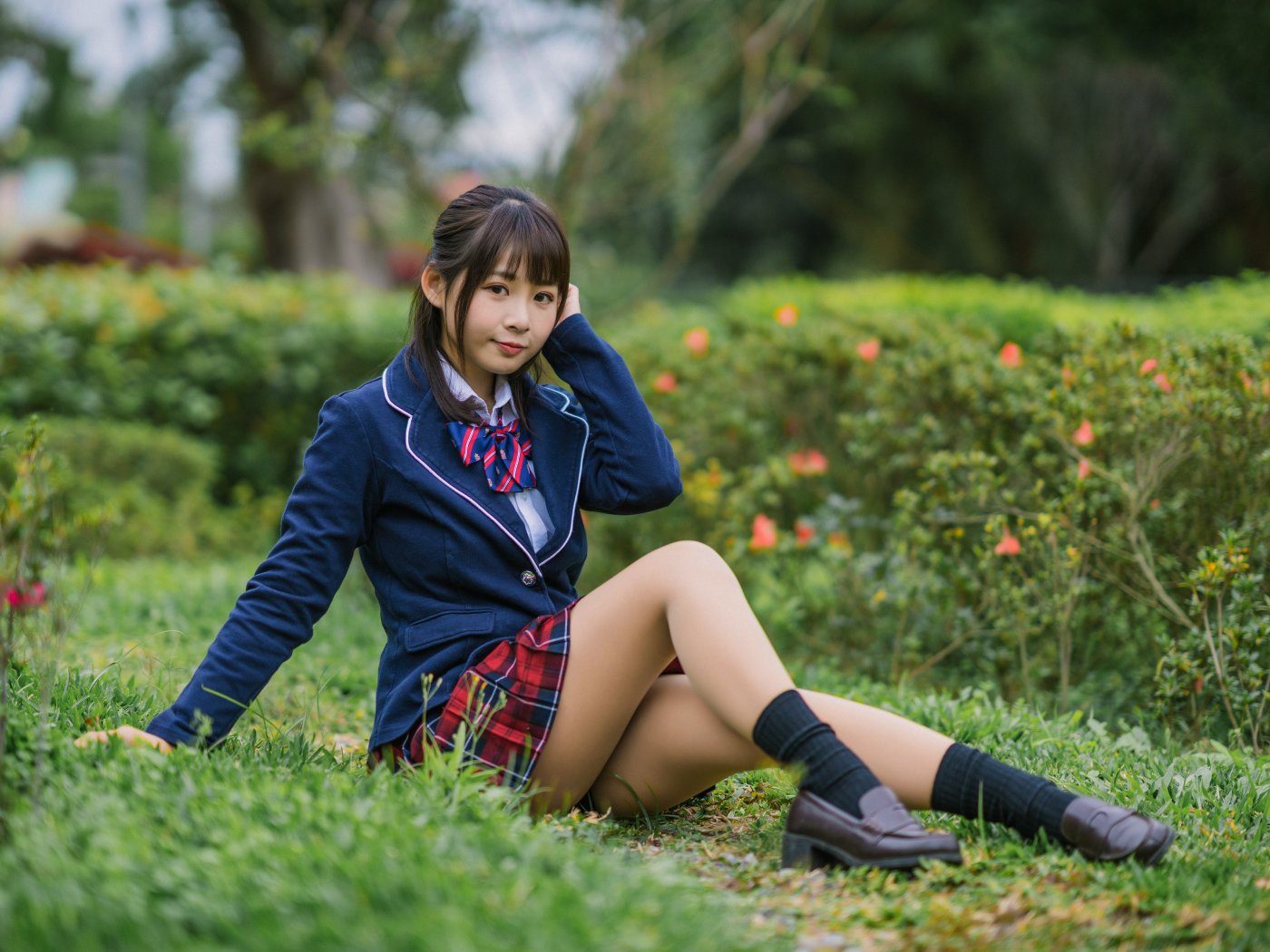 Азиатская школьница сидит на траве