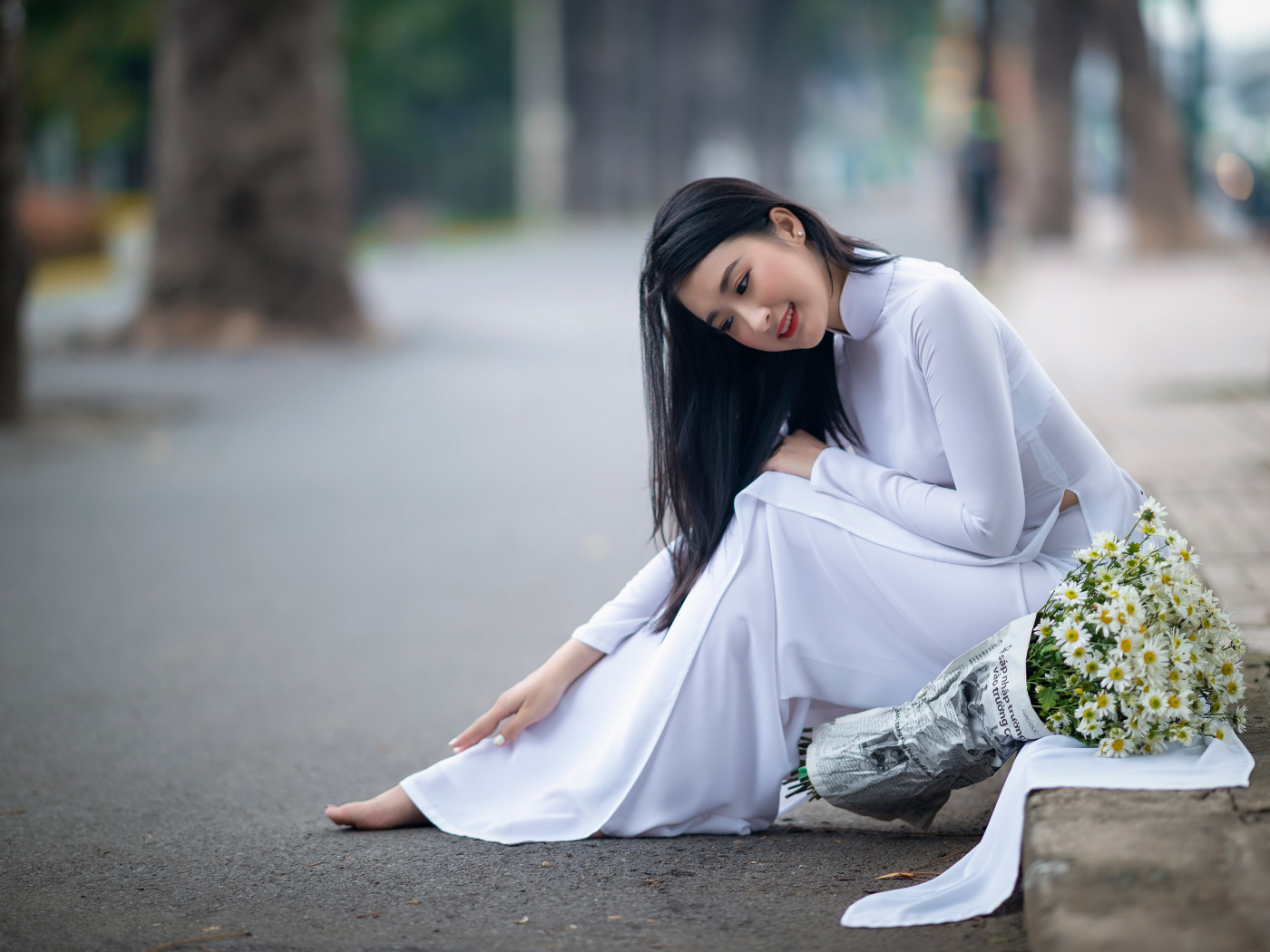 Красивая девушка азиатка в белом платье с букетом ромашек