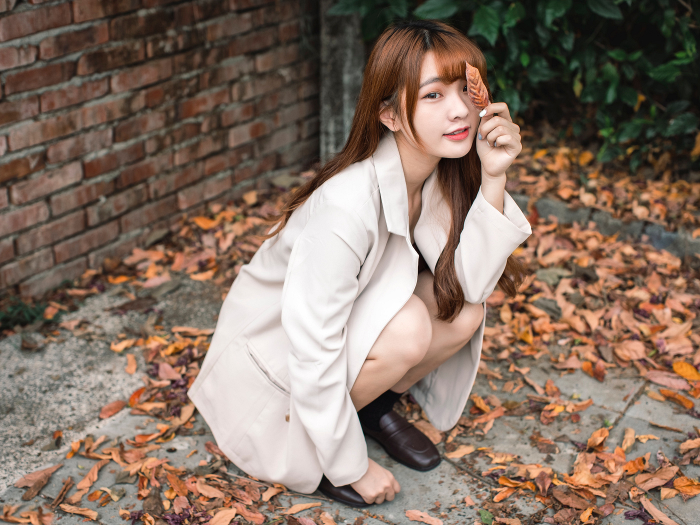 Красивая девушка азиатка на земле с опавшей листвой 