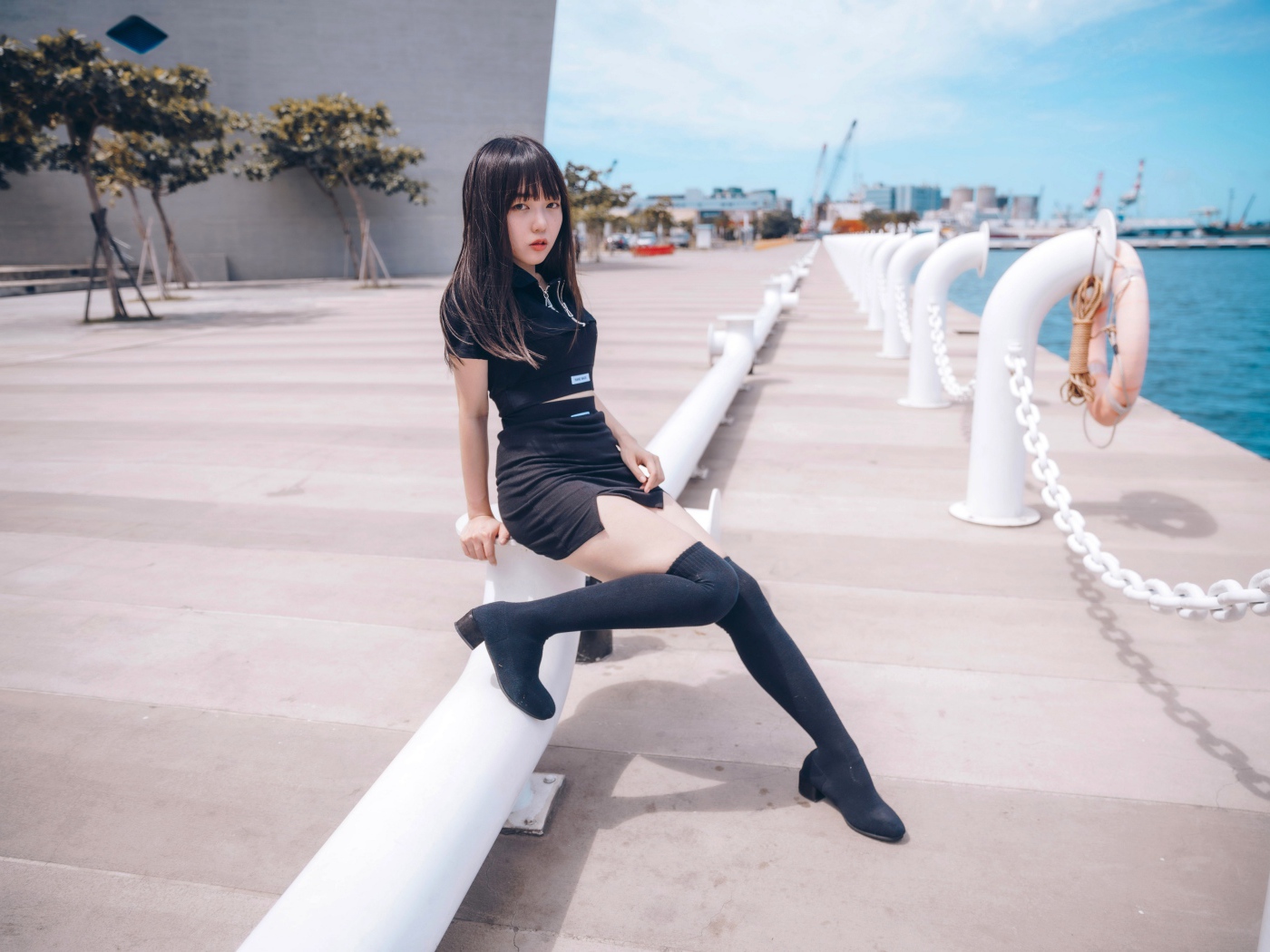 Красивая девушка азиатка в черных сапогах на причале