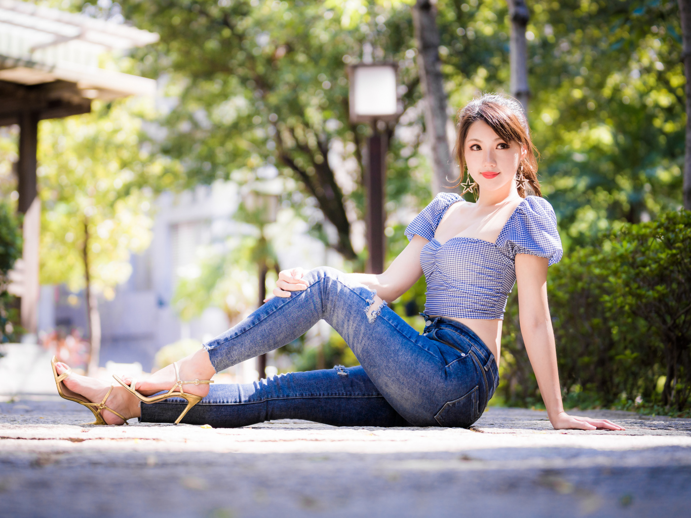 Красивая азиатка в джинсах сидит на земле