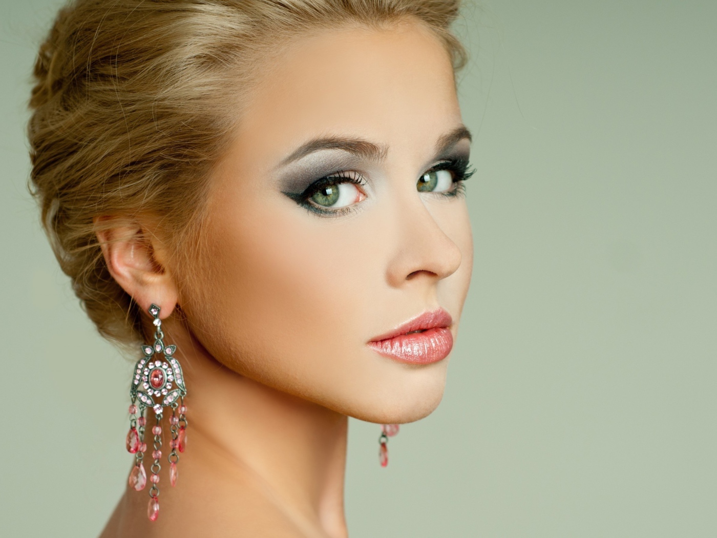 Красивая девушка блондинка с красивыми сережками на сером фоне