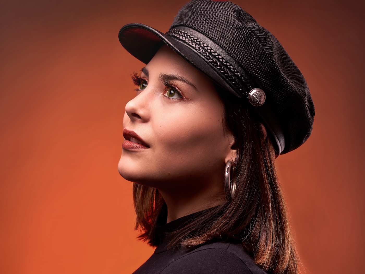 Красивая девушка в кепке на коричневом фоне