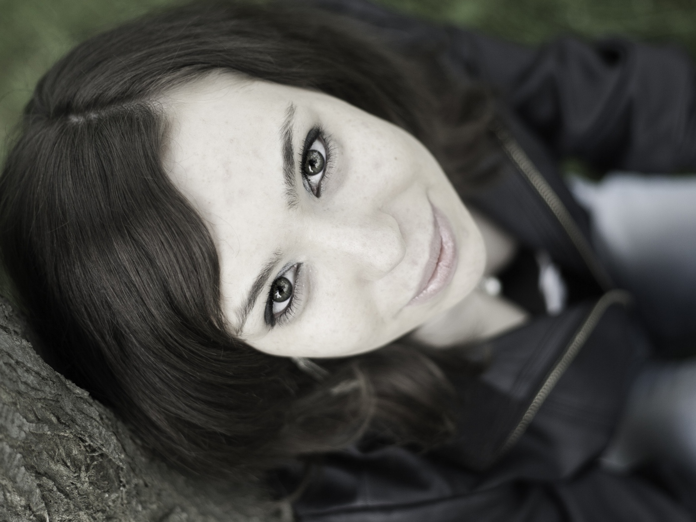 Красивая девушка смотрит вверх сидя под деревом  