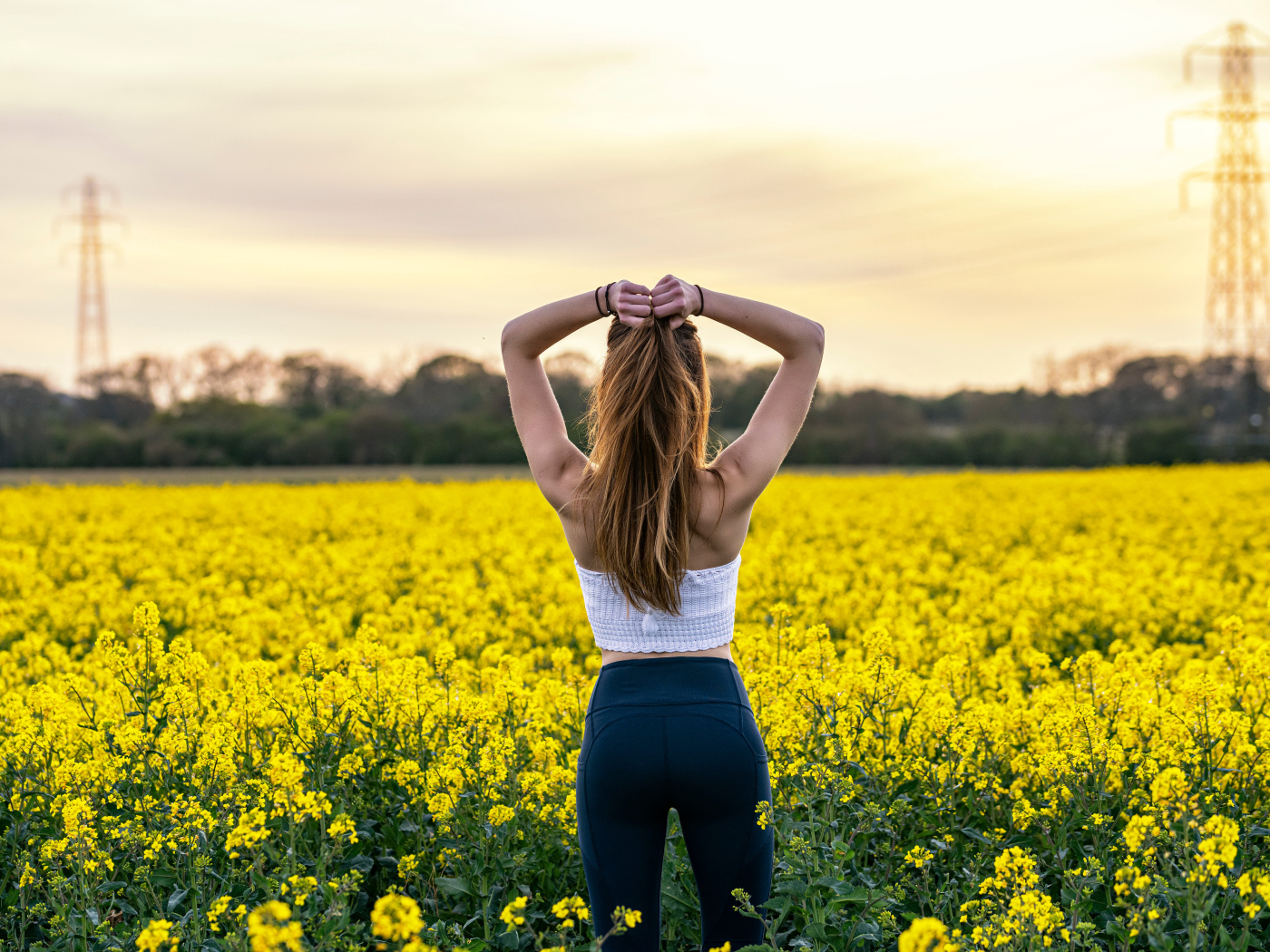 Красивая девушка стоит на поле с рапсом