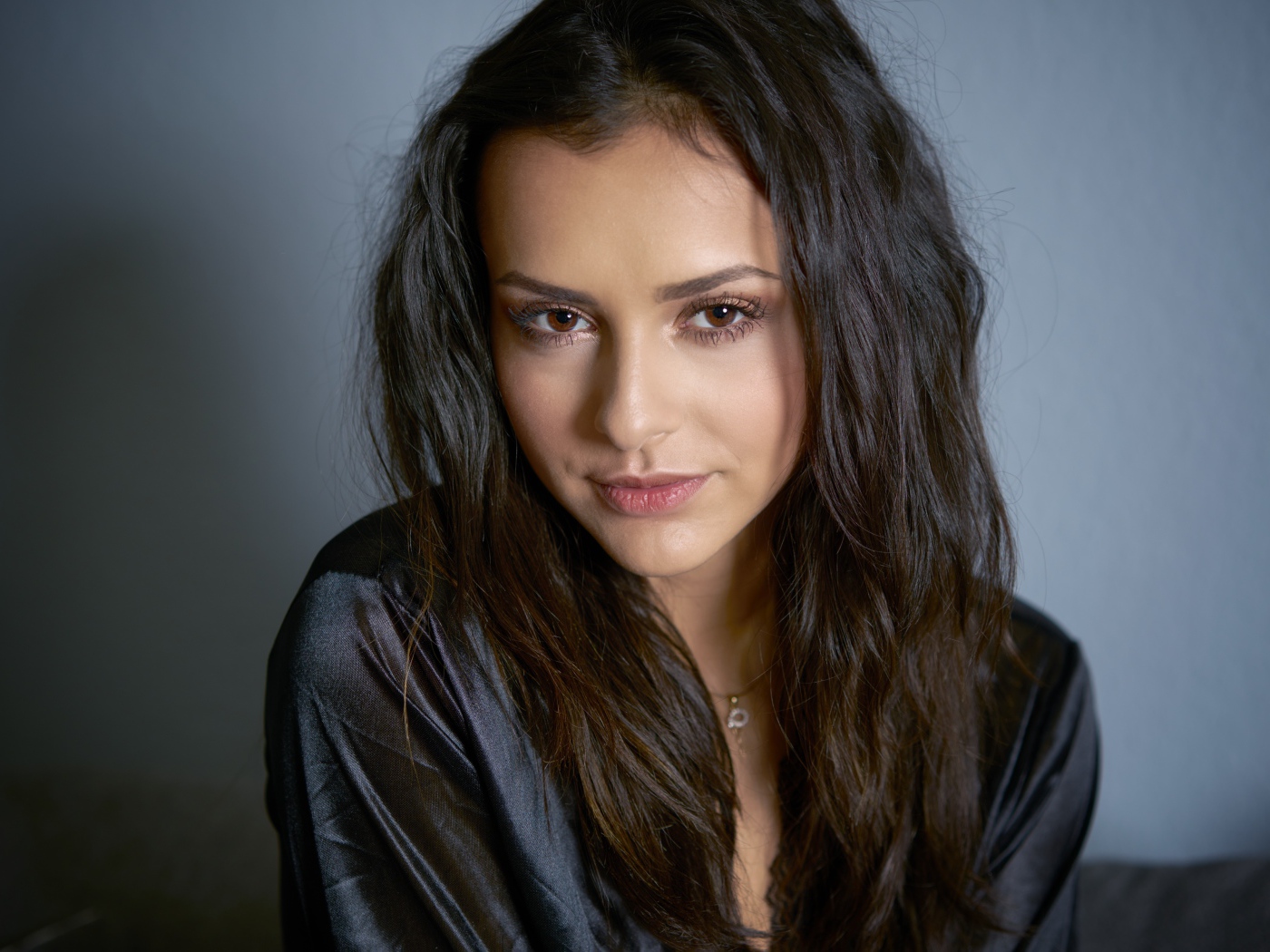 Кареглазая брюнетка в черном халате на сером фоне