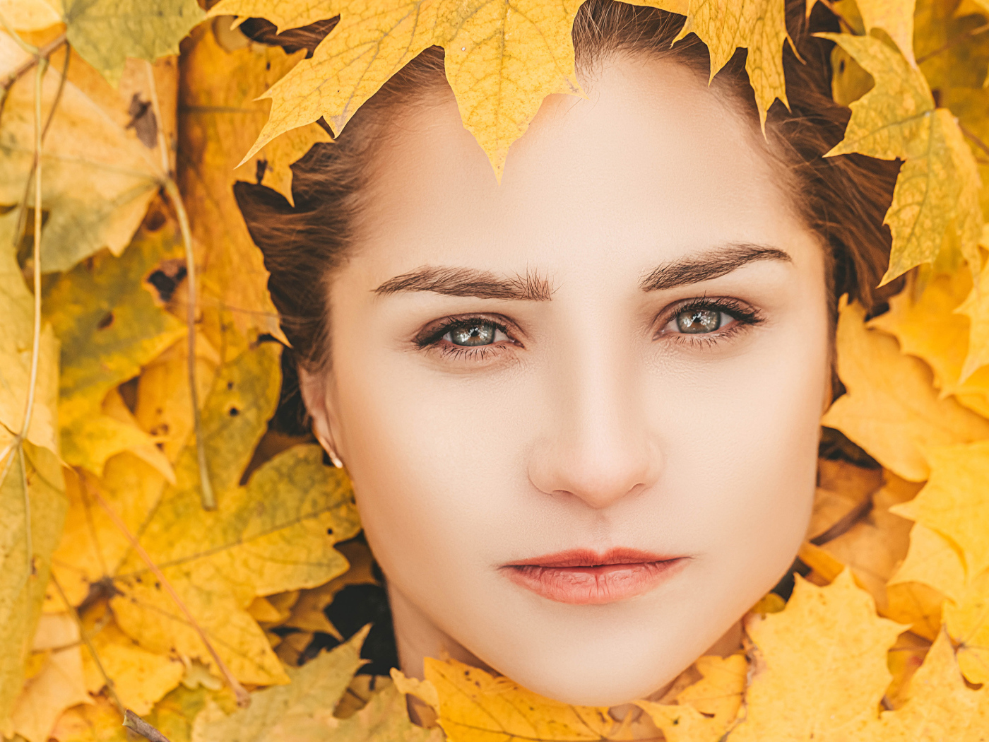 Лицо красивой молодой девушки в желтой листве
