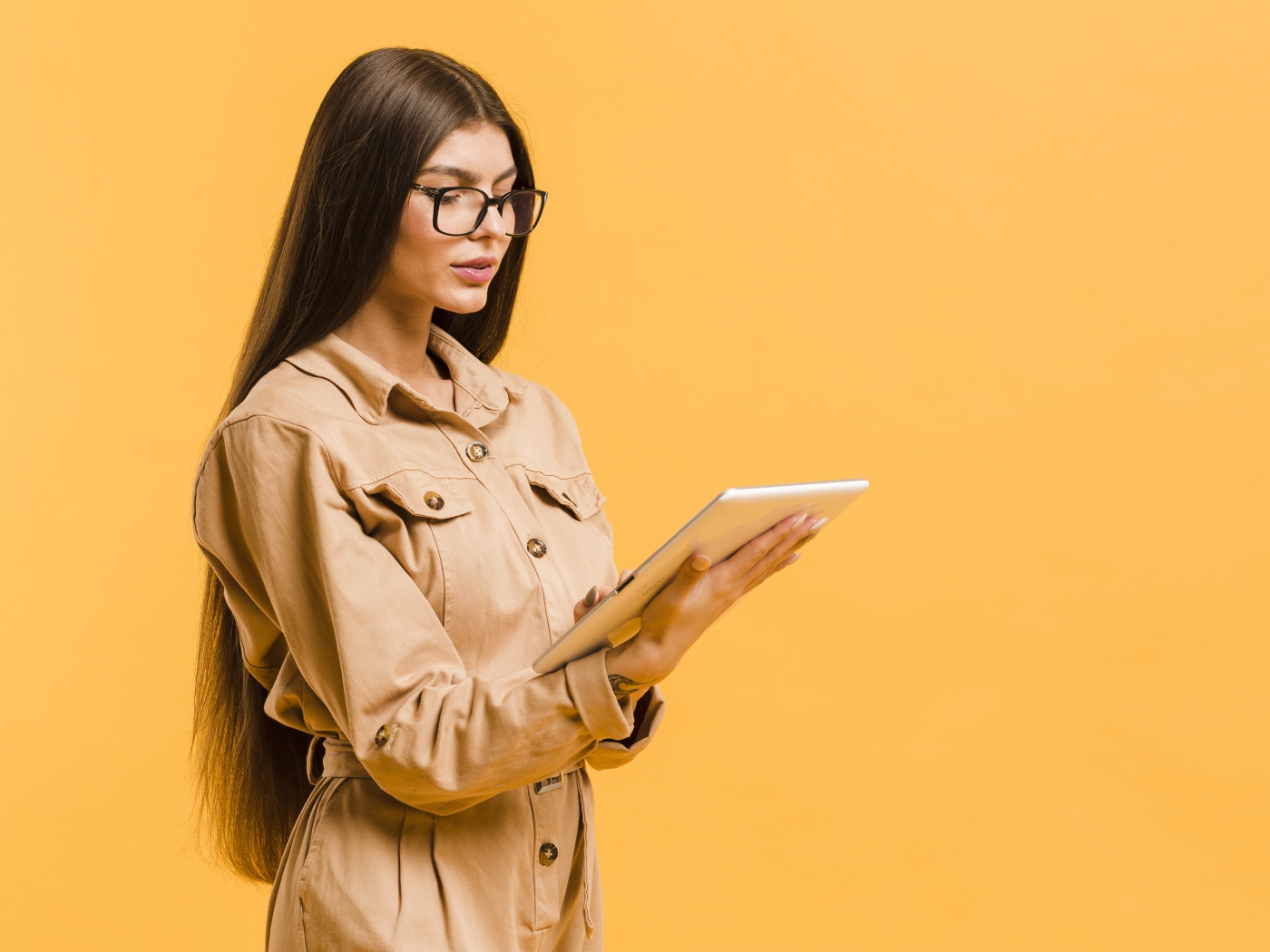 Девушка с планшетов руках на желтом фоне