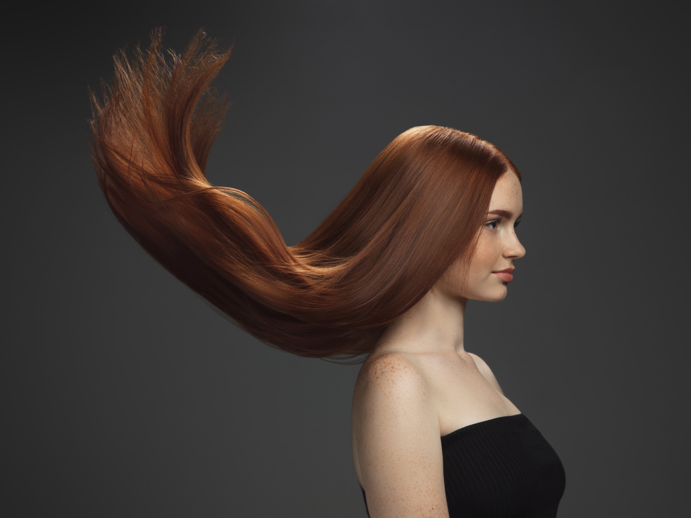 Волосы подняты вверх у красивой девушки на сером фоне