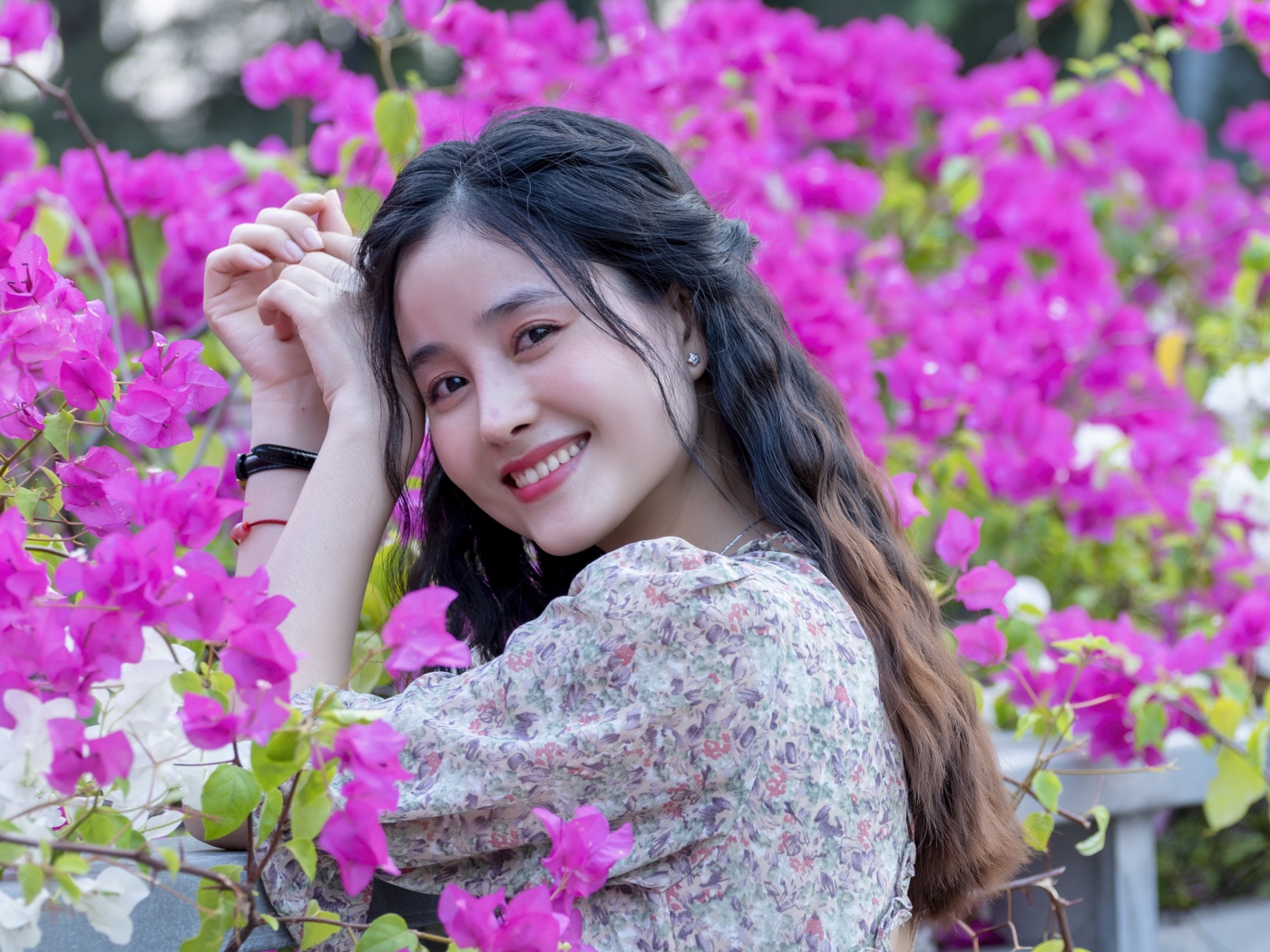 Улыбающаяся девушка азиатка на фоне розовых цветов