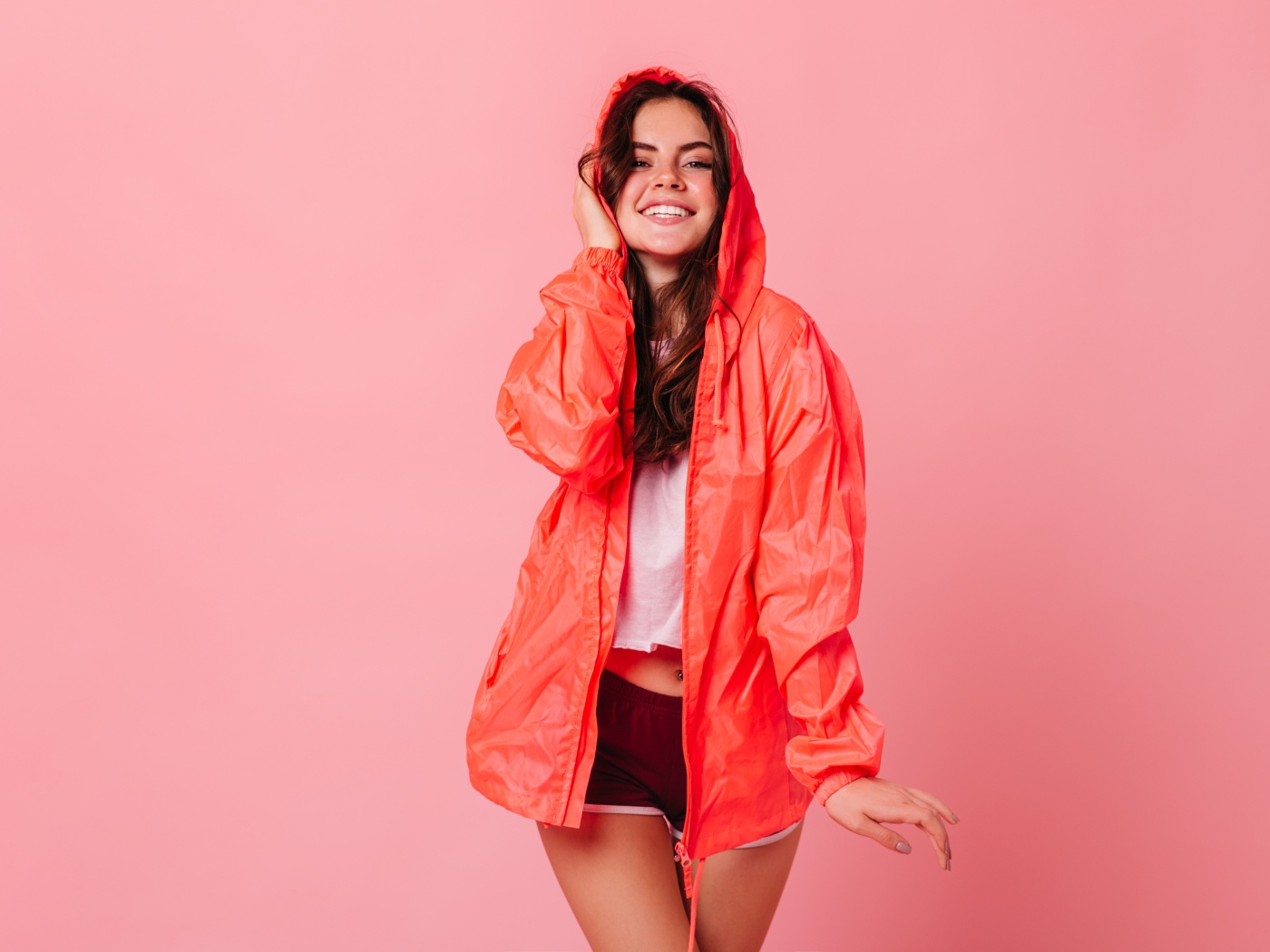 Улыбающаяся девушка в плаще на розовом фоне