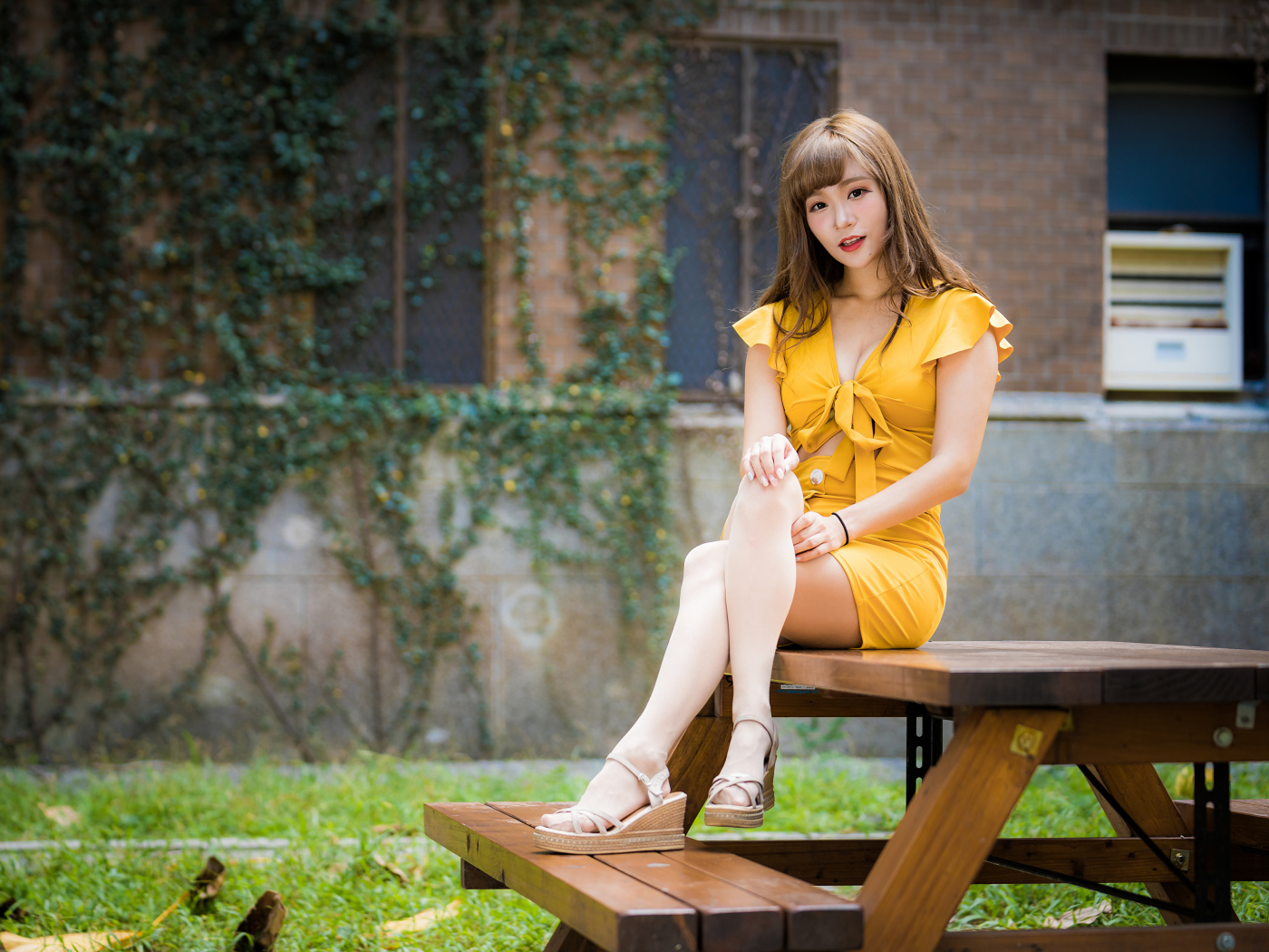 Молодая азиатка сидит в парке на столе 