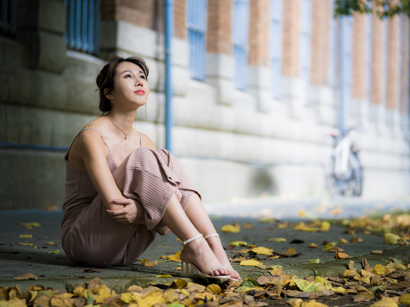 Молодая девушка азиатка сидит на земле с листьями 