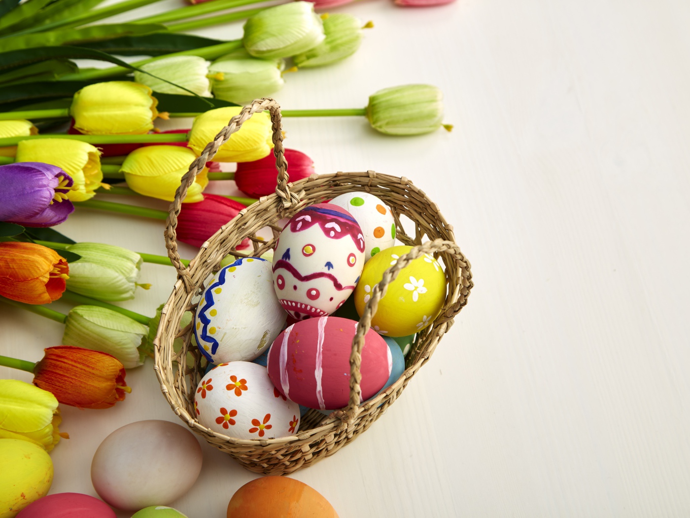 Корзина крашеных яиц с букетом тюльпанов