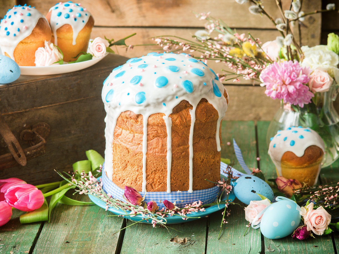 Красивый пасхальный кулич с белой глазурью на столе с цветами