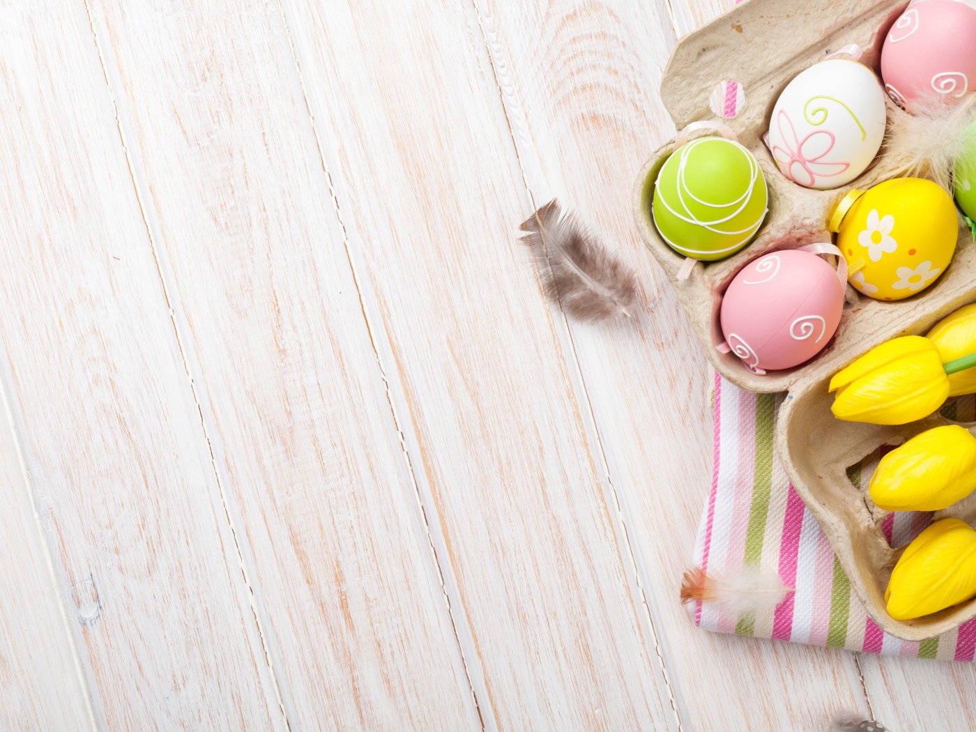 Крашеные пасхальные яйца на столе с тюльпанами