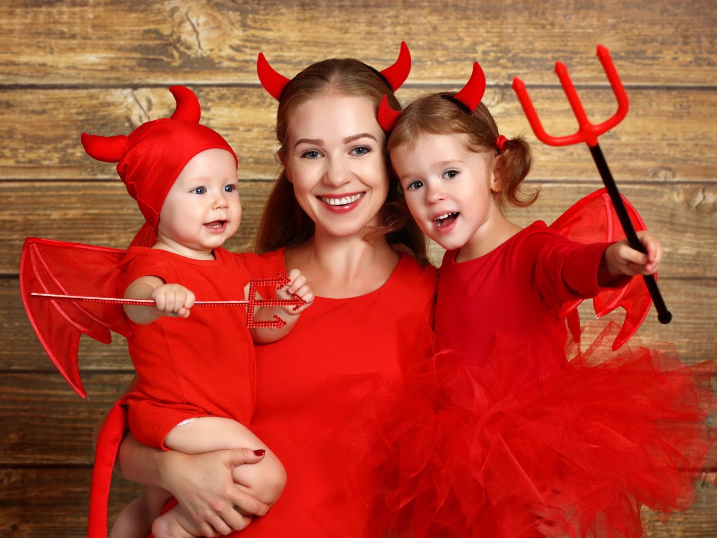 Женщина с двумя детьми в красных костюмах на Хэллоуин