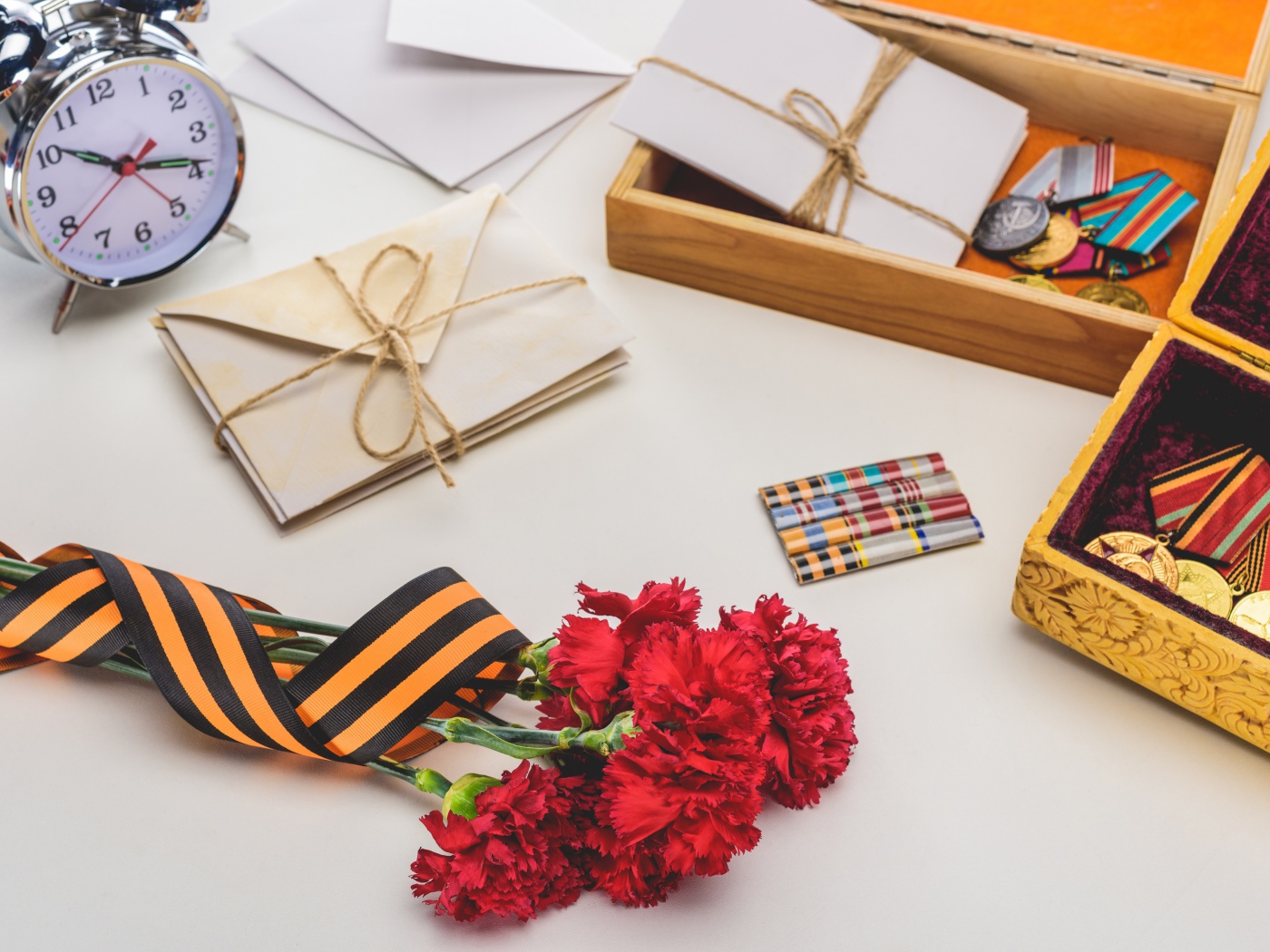 Букет красных гвоздик, ордена и часы на День победы 9 мая