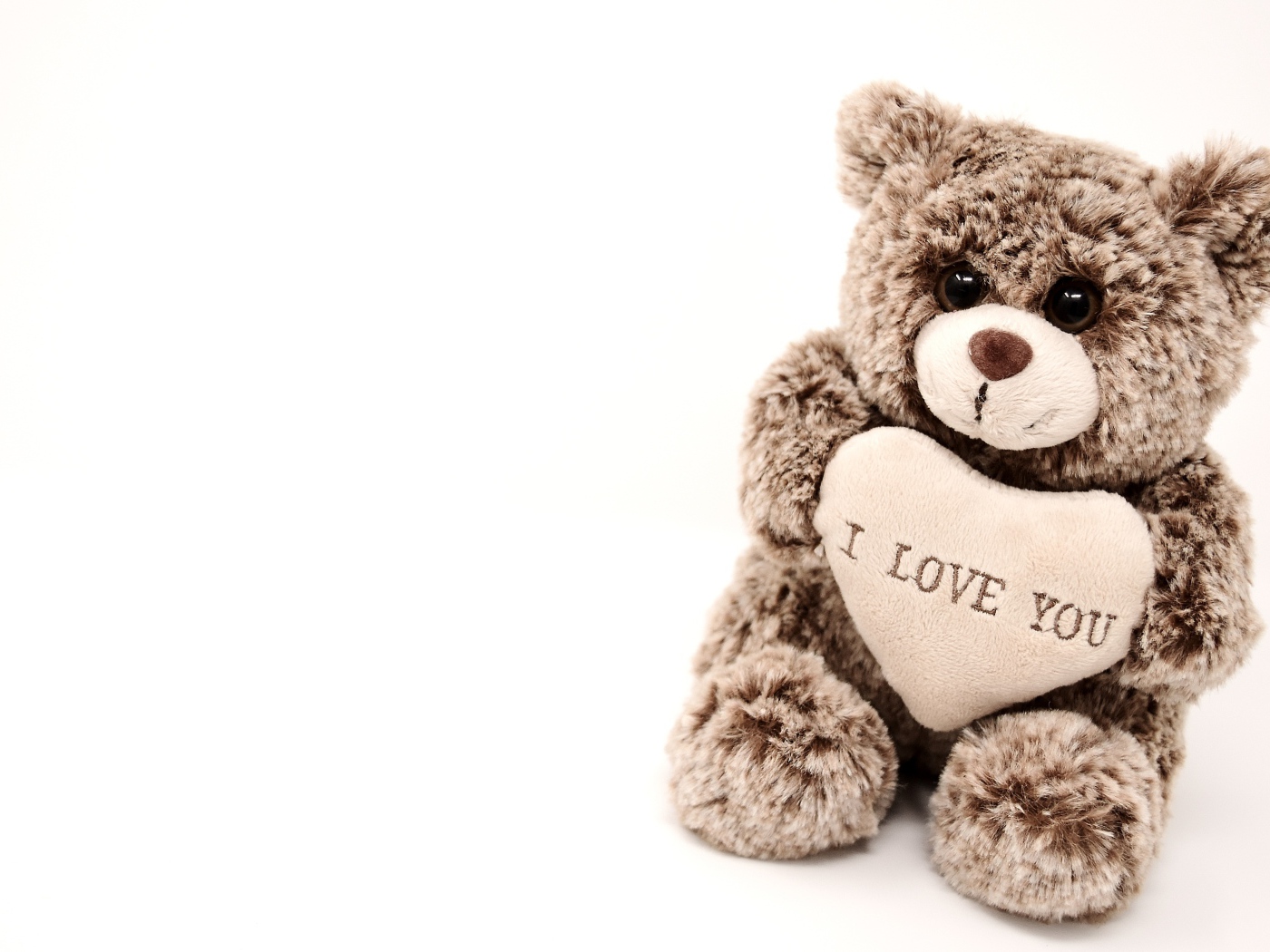 Меховая игрушка медвежонок с сердцем на белом фоне