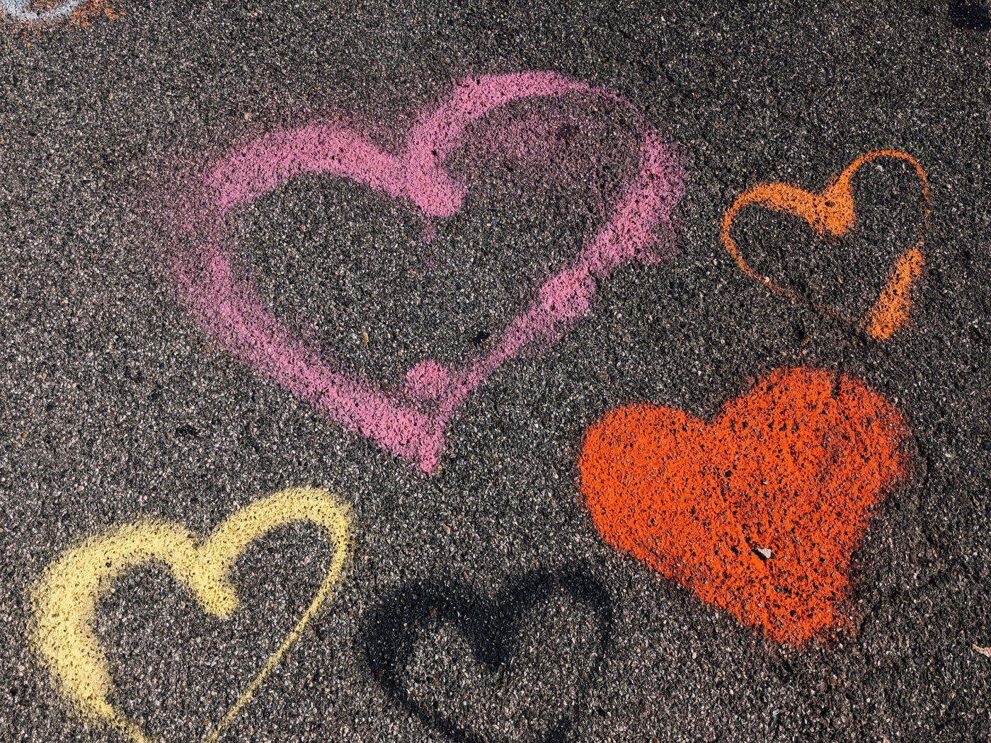 Hearts with multicolored chalk on the asphalt