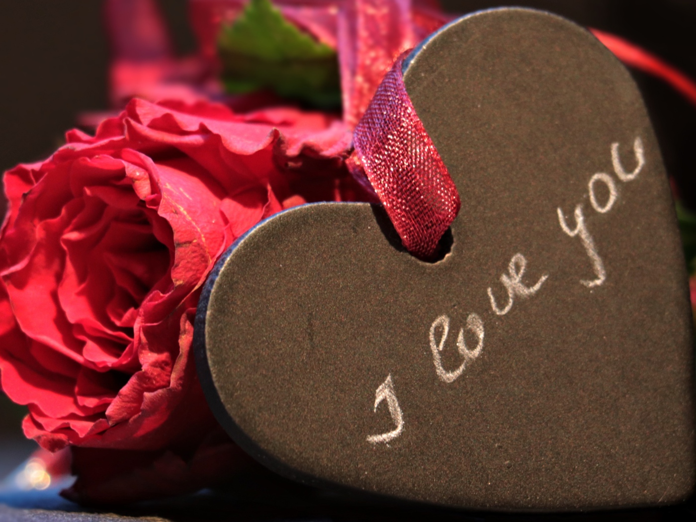 Каменное сердце с ленточкой на столе с розой 