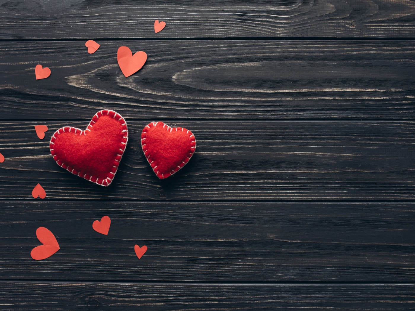 Два больших  красных сердца с маленькими  на деревянном столе 