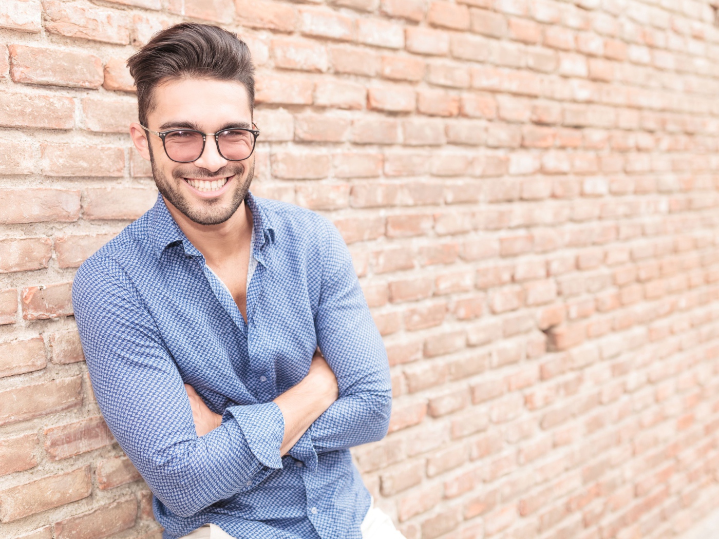 Smiling man with glasses standing against the wall